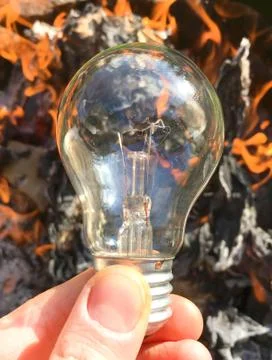 Light bulb in hand on a background of fire, texture Stock Photos