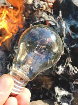 Light bulb in hand on a background of fire, texture Stock Photos