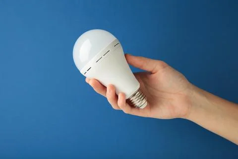 Light bulb in hand on blue background. Space for text Stock Photos