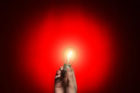 Light bulb in hand on red background Stock Photos