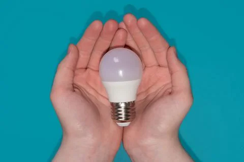Light bulb in hands on the blue background. Foto stock