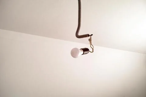 Light bulb hanging on the wire on the ceiling. Stock Photos