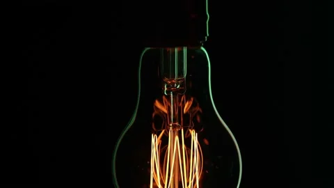 A light bulb hangs in the dark and pulses with light close up. Stock Footage 149196682