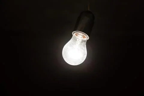 Light bulb illuminates a dark room. Stock Photos