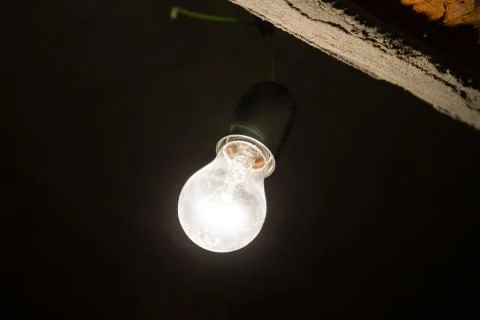Light bulb illuminates a dark room. Stock Photos