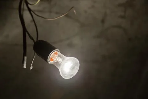 Light bulb illuminates a dark room. Stock Photos