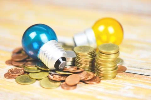 Light bulb with light from the lamp on stacked coins on a wooden table backgr 스톡 사진
