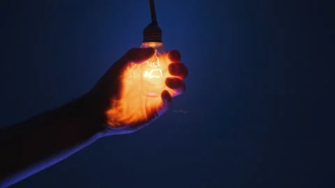 The Light Bulb Lights Up And Flickers in the Male Hand on Dark Blue Background Stock Footage 235440920