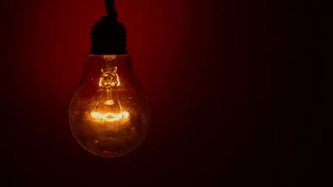 Light Bulb Lights Up and Goes Out on a Red Background in the Dark Video stock 233831370