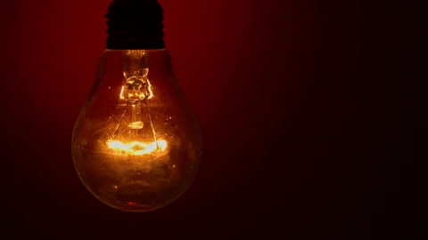 Light Bulb Lights Up and Goes Out on a Red Background in the Dark Stock Footage 234523232