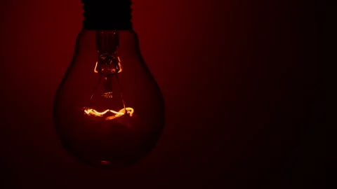 Light Bulb Lights Up on a Red Background in the Dark Stock Footage 236934405