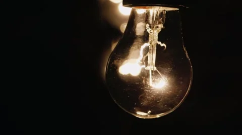 Light bulb lit brightly against a black background 库存影片 58554903