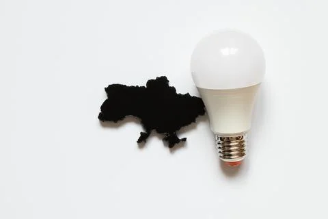 A light bulb next to a black, three-dimensional outline of a map of Ukraine.. Stock Photos