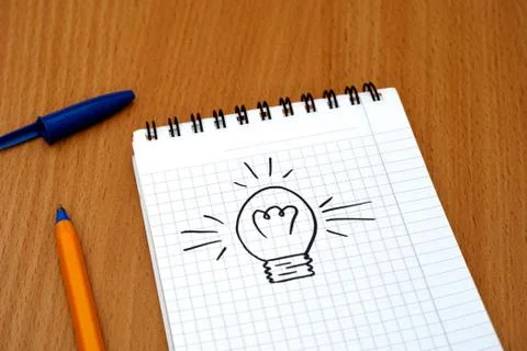 Light bulb painted on note pad with pen Stock Photos
