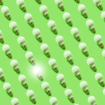 Light bulb pattern with one glowing on the corner on a light green background Stock Photos