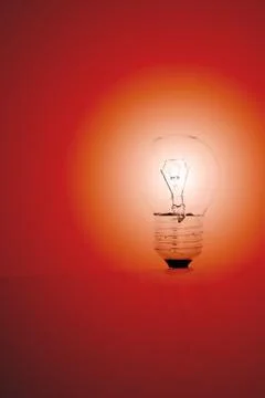 Light bulb on a red background Stock Photos