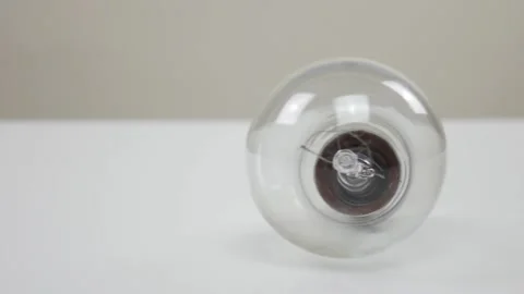 Light bulb rolling on white table Stock Footage 105371946