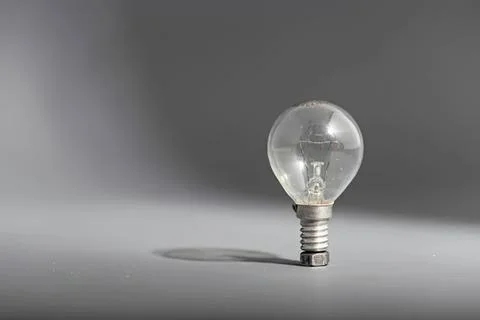 Light bulb standing on a gray surface with shadow Stock Photos