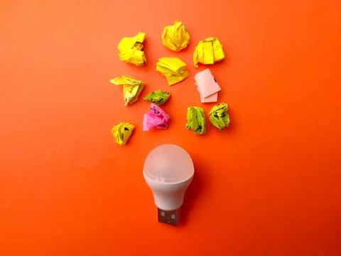 Light bulb surrounded by several pieces of colorful crumpled paper 写真素材