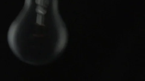 Light bulb swinging and turning on and off. Slow motion. Stock Footage 72607604