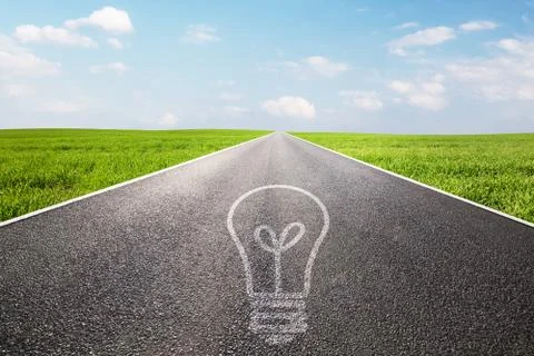 Light bulb symbol on long empty straight road. Environment, idea Stock Photos