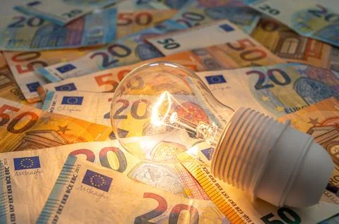 Light bulb on, on top of banknotes. Stock Photos