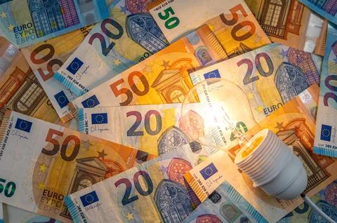 Light bulb on, on top of banknotes. Stock Photos