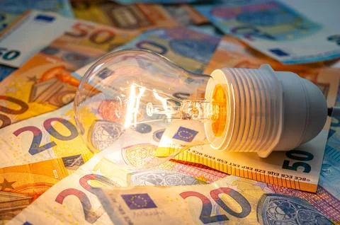 Light bulb on, on top of banknotes. Stock Photos