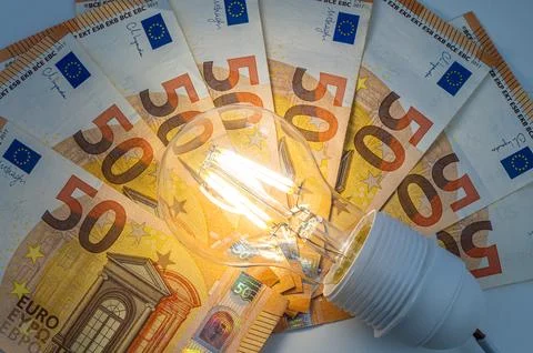 Light bulb on, on top of banknotes. Stock Photos