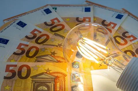Light bulb on, on top of banknotes. Stock Photos