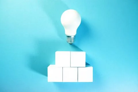 Light bulb on top of a stack of white cubes on a blue background Stockfoto's
