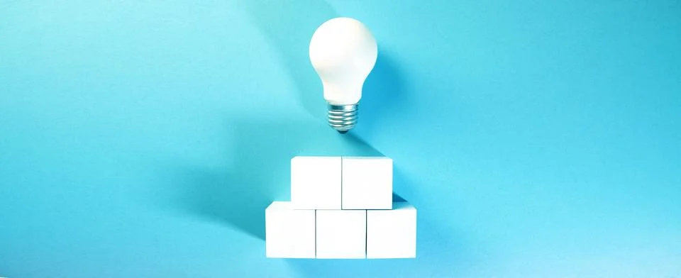 Light bulb on top of a stack of white cubes on a blue background 스톡 사진