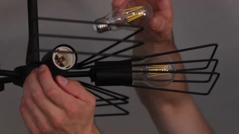 Light bulbs are being twisted into the designer chandelier Stock Footage 113788238