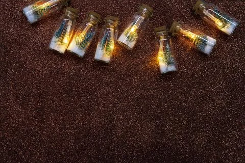 Light bulbs inside with Christmas tree and snow on brown shiny background Stock Photos