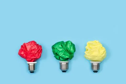 Light bulbs made with colored crumpled papers on a light blue background Stock Photos