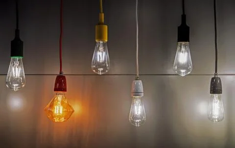 Light bulbs with multi-colored electric cords on a dark background. Stock Photos