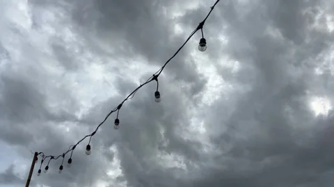 The light bulbs swayed and hung against the backdrop of the dark sky. 스톡 동영상 320810778