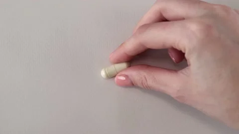 Light capsule of supplements, vitamins, minerals or trace elements in a woman's Stock Footage 235551323