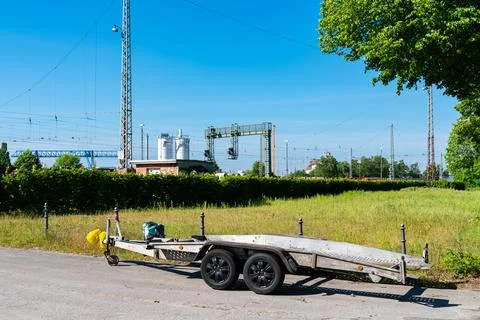 Light car trailer standing on the side of the road. Stock Photos