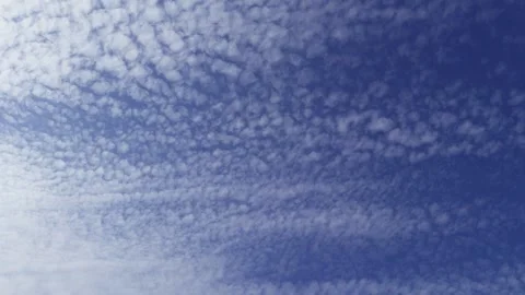 Light, cirrus clouds scattered across a bright blue sky Stock Footage 315439865