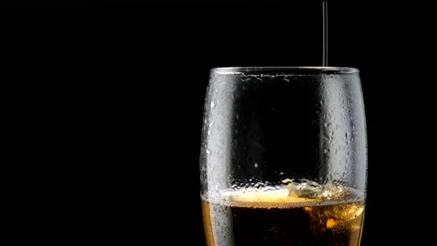 Light cold beer pours into a wet glass. With bubbles and foam. Black background. Stock Footage 136385024