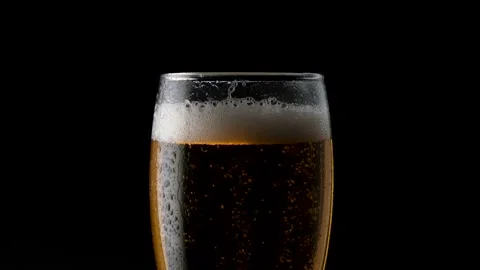 Light cold beer pours into a wet glass. With bubbles and foam. In the center of Stock Footage 136389651