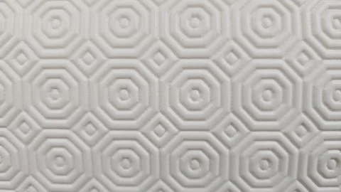  Light colored textured surface displaying a repeating geometric arrangem.. 스톡 사진