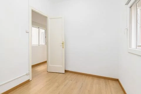 Light compact room with a small window and white walls with an open front door Stock Photos