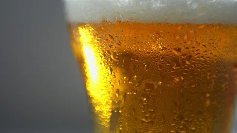 Light craft beer, bubbles rise up. A misted glass, a drop drains. Stock Footage 123051766