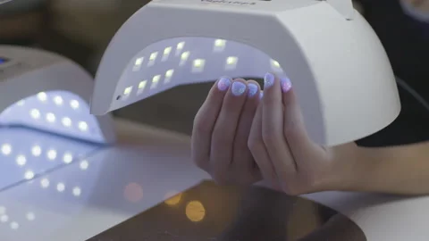Light curing process on young wowan's nails in manicure salon 스톡 동영상 231355491