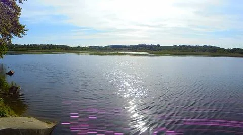 Light damaged image of pond in summer under partly cloudy sky. Stock Photos