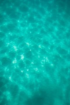 Light dancing on the sand below a tropical turquoise blue ocean Stock Photos
