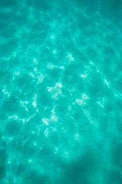 Light dancing on the sand below a tropical turquoise blue ocean Stock Photos