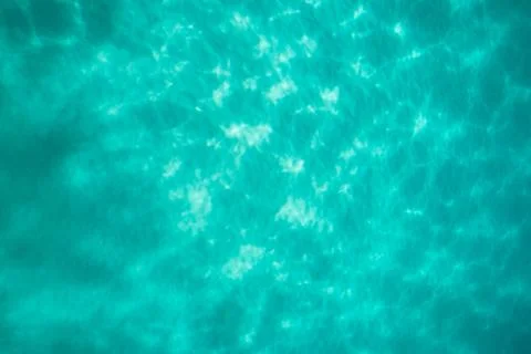 Light dancing on the sand below a tropical turquoise blue ocean Stock Photos